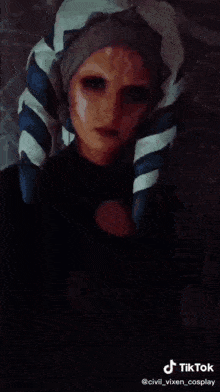 a woman in a cosplay costume is standing in front of a red light .