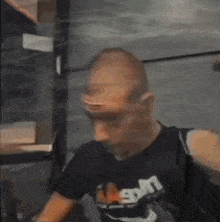 a man with a shaved head is wearing a black t-shirt with the word n on it .