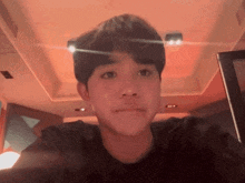 a young man in a black shirt is taking a selfie in a room .