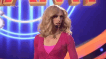 a woman in a wig is standing on a stage with a microphone in her mouth .