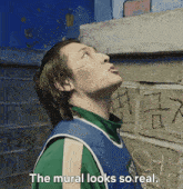 a man looking up at a brick wall with the words the mural looks so real