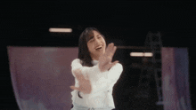 a woman in a white shirt is dancing in a dark room and laughing .