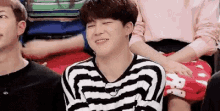 a man in a black and white striped shirt is laughing while sitting in a crowd of people .