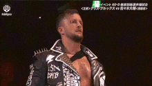 a man with a beard is holding a gold wrestling championship belt in a dark room .