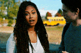 a man and a woman are standing in front of a yellow school bus .