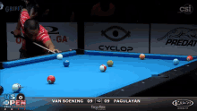a man playing pool with a cyclop logo on the wall behind him