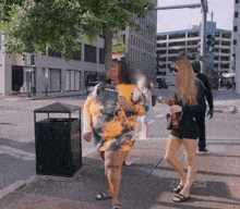 a woman wearing a tie dye dress is walking down a street