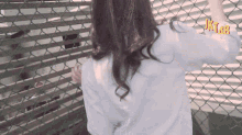 a woman is standing in front of a chain link fence with jktub written on the bottom right