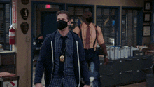 a man wearing a mask is standing next to another man in an office