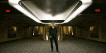 a man stands in a hallway with a red exit sign