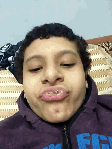 a boy wearing a purple jacket with the word fifty on it makes a funny face