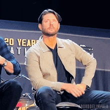 a man sitting in front of a sign that says 20 years at