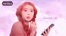 a woman with red hair is holding a cell phone in front of a sign that says ' korean ' on it