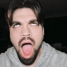 a man with a beard is making a funny face with his tongue sticking out