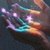 a close up of a person 's hands with a rainbow of colors and sparkles coming out of them .