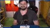 a man with a beard wearing headphones is sitting in front of a microphone and smiling .
