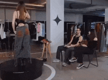 a woman is standing on a platform in a room while a man sits in a chair .