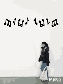 a woman is walking in front of a white wall with music notes written on it