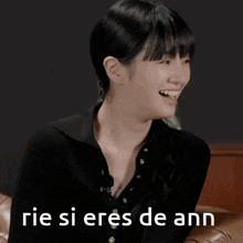 a woman is laughing while sitting on a couch and the words rie si eres de ann are on the bottom