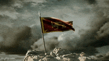 a flag with a lion on it is waving on top of a mountain