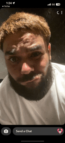 a man with a beard is on a phone screen with the words send a chat
