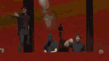 a group of people are standing next to each other on a red background .