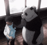 a man and a panda bear are standing next to each other in front of a window