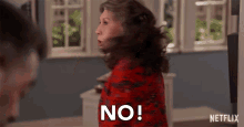 a woman in a red dress is saying no in front of a window