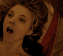 a close up of a woman laying on a bed with her mouth open