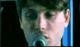 a young man singing into a microphone with a blue background