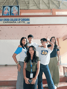 a group of people are posing in front of a sign that says oly cross college of caricara