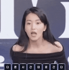 a woman in a black off the shoulder top is making a funny face while standing in front of a microphone .