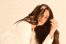 a woman in a white shirt is holding her hair