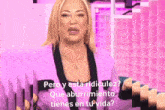 a woman in a pink suit is talking in spanish while standing in front of a pink background .