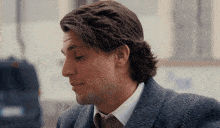 a close up of a man 's face with a white shirt and a blue jacket