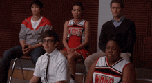 a group of people are sitting in chairs and one of them is wearing a wmhs jersey