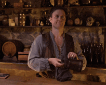 a man standing behind a counter with a bottle in his hand