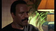 a man with a mustache and a black shirt looks at the camera