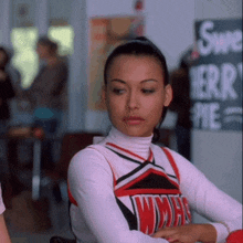 a cheerleader in a wmhs uniform sits in front of a sign that says sweet