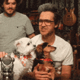 a man is holding two small dogs in his arms
