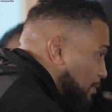 a close up of a man 's ear with a beard