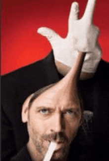 a man in a top hat is smoking a cigarette and making a peace sign with his hand