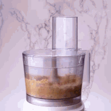 a food processor filled with a brown substance and a knife in the middle