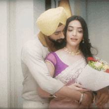 a man in a turban is hugging a woman in a purple top and white saree