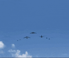 a group of military planes are flying in a blue sky .