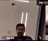 a man with a beard is standing in front of a microphone with a purple sticker that says 90k