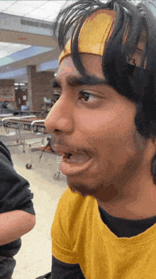 a man wearing a yellow shirt and a headband is making a face