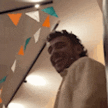 a man in a white shirt is smiling in a room with triangles on the ceiling .