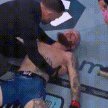 a man is laying on the ground in a boxing ring while a referee watches .