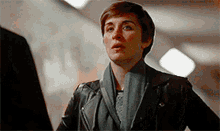 a woman wearing a scarf and a leather jacket looks surprised